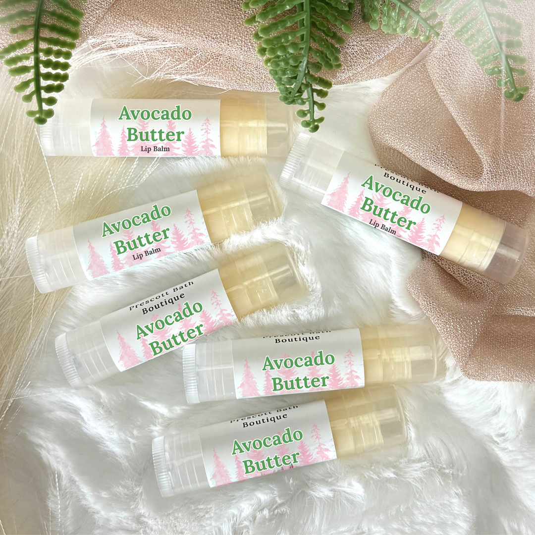 Avocado Butter lip balm tubes on a soft fabric background with green leaves.