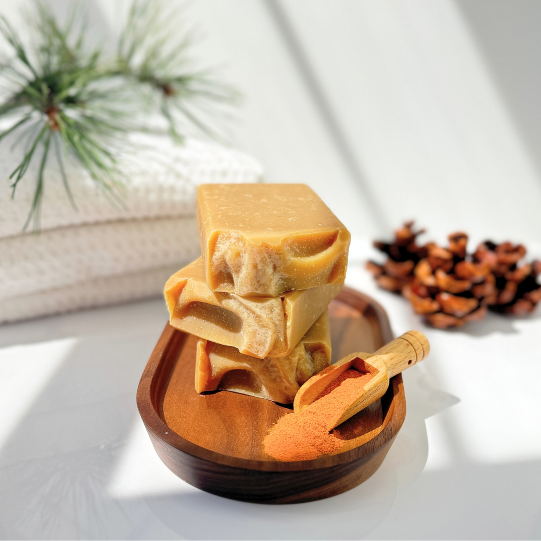 Stack of soap bars in a wooden bowl with a wooden spoon on a light background