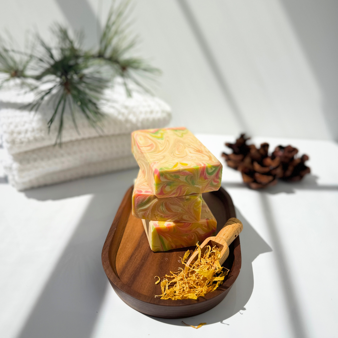 Three colorful soap bars on a wooden dish with a white background